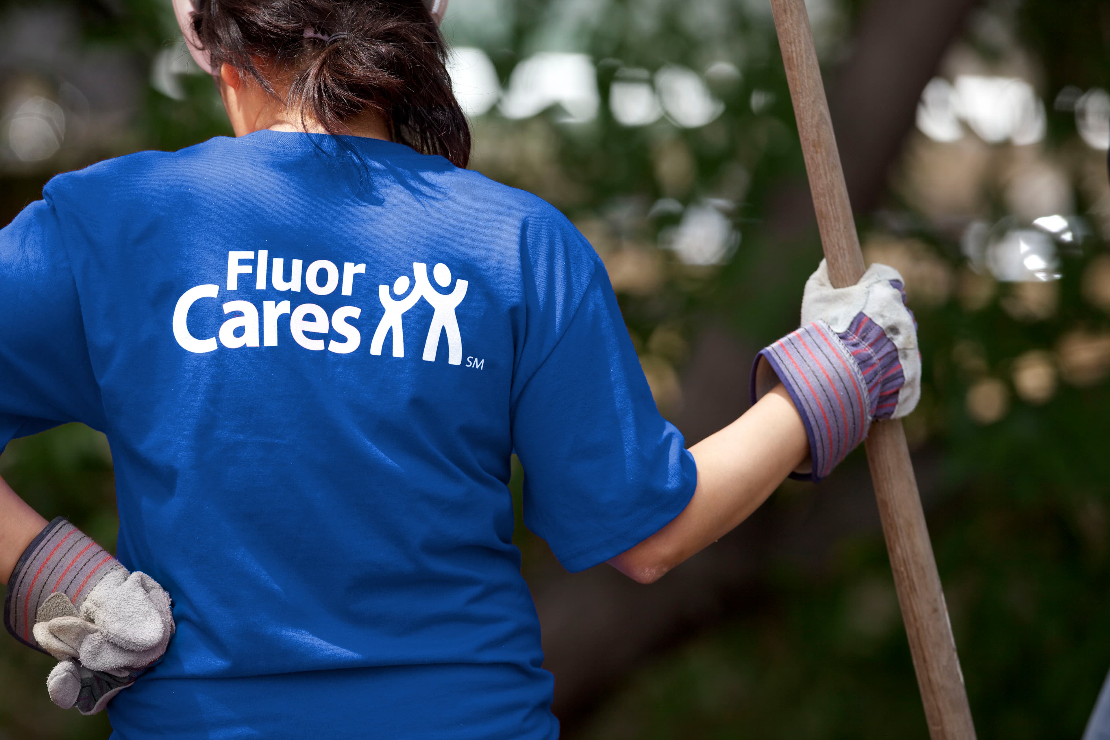 Woman with blue Fluor Cares t-shirt and landscaping tool